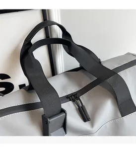 Dettaglio dei manici rinforzati e del tessuto in nylon della borsa da viaggio grigia