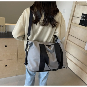 Sac de voyage gris imperméable avec bandoulière noire porté par un mannequin de dos