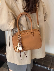 Borsa Boston in pelle marrone stile vintage con ciondolo baseball su trench kaki