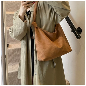 Brown suede Hobo bag with knot shoulder strap detail shown on a model in a stairwell