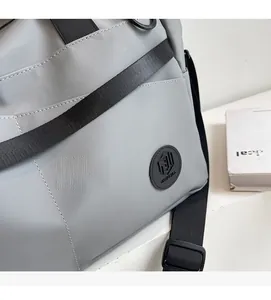 Dettaglio della borsa da viaggio grigio chiaro con logo MINGJIA e tracolla in nylon