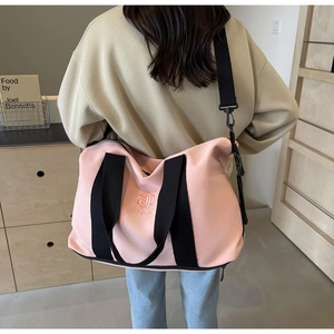 Détail du sac de voyage rose avec poignées noires et broderie du logo Ningjia