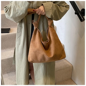 Detail of caramel brown suede tote bag featuring a unique knotted handle design