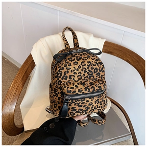 Close-up detail of leopard print mini backpack with canvas texture and dual zipper pockets