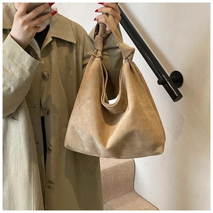 Close-up of brown suede tote bag featuring a decorative knot on the shoulder strap