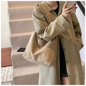 Close-up of a large vintage khaki suede tote bag carried by a model on stairs