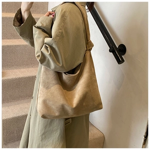 Detail of light brown matte suede tote bag with knotted shoulder strap on camel trench coat