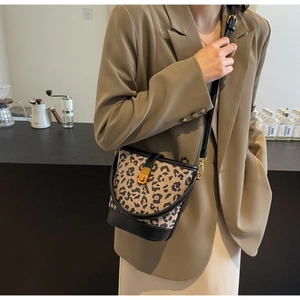 Dettaglio della borsa a secchiello leopardata con base in pelle nera e chiusura dorata