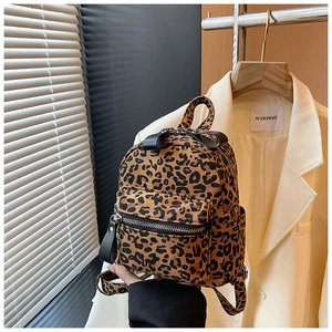 Close-up of leopard print mini backpack showing canvas texture and zipper front pocket