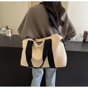 Détail du sac de voyage en toile beige avec sangles noires et bandoulière amovible