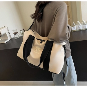 Vue arrière d'un mannequin portant un grand sac de voyage beige dans un café moderne