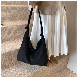 Detail of a large black matte tote bag featuring a unique knot detail on the shoulder strap