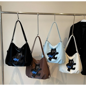 Détail de sacs hobo à motif chat en quatre couleurs sur un cintre métallique