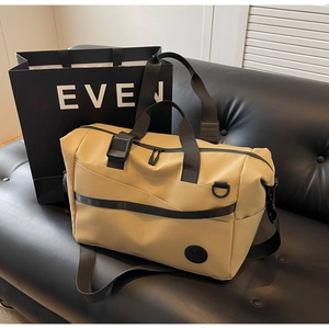 Dettaglio borsa da viaggio kaki su divano in pelle con manici resistenti e logo