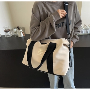 Gros plan du sac de voyage en toile crème avec logo NINGJIA et bandoulière noire réglable