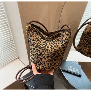 Detail of leopard print tote bag featuring brown leather strap and gold chain hook