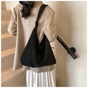 Close-up of black matte tote bag featuring stylish knotted strap and soft suede texture
