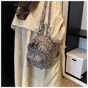 Detailed side view of a leopard print mini backpack worn with a stylish trench coat