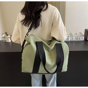 Détail du sac de voyage en toile vert avocat avec logo brodé et bandoulière noire