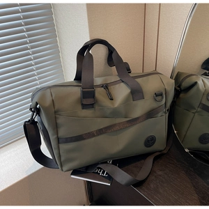 Dettaglio della borsa da viaggio verde militare con tracolle nere e tasca laterale a zip