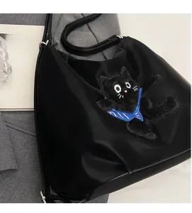 Détail du sac cabas en nylon noir avec écusson chat en peluche et anses en cuir