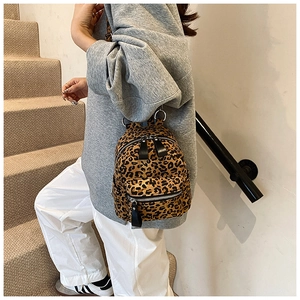 Detail of a mini leopard print backpack with dual zippers shown on a model