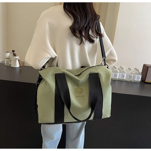 Sac de voyage vert olive à grande capacité porté par un modèle avec sangle réglable