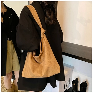 Detail of the knotted shoulder strap on a brown matte suede hobo bag for women
