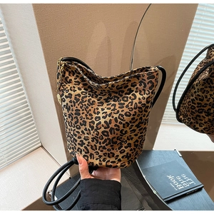 Close-up of leopard print bucket bag featuring black leather trim and gold metal chain strap