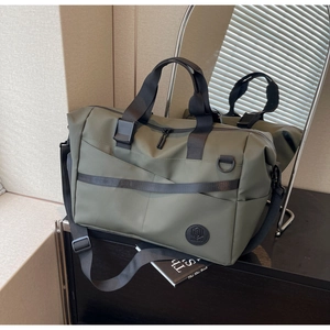 Dettaglio della borsa da viaggio verde oliva con manici neri su una scrivania scura