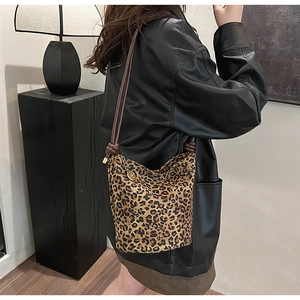 Detailed view of leopard print bucket bag with gold pendant and cylindrical shoulder strap