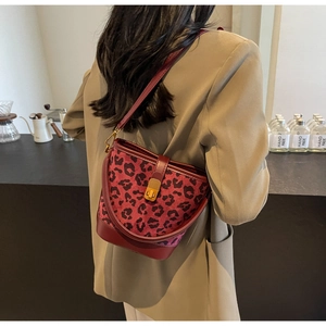 Detail der burgunderroten Eimertasche mit Leopardenmuster und goldenem Drehverschluss