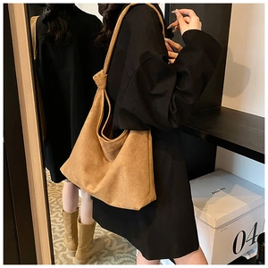 Close-up of a brown suede tote bag with a minimalist knotted handle and boho design