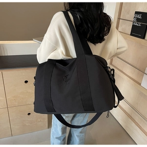 Vue détaillée du sac de voyage en nylon noir avec bandoulière et grande capacité