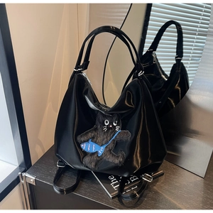 Détail du sac cabas noir brillant avec un écusson de chat en peluche 3D et broderie
