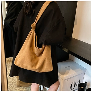 Detail of camel suede tote bag showing minimalist design and unique knotted shoulder strap