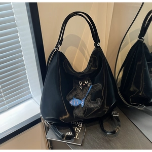 Détail du sac Hobo noir avec broderie chat en peluche portant un petit poisson bleu
