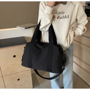 Détail d'un sac de voyage noir multifonctionnel avec logo et larges sangles en nylon