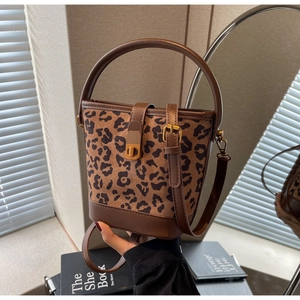 Dettaglio borsa a secchiello leopardata con manico in pelle marrone e chiusura dorata
