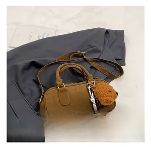 Dettaglio ravvicinato della borsa Boston in camoscio marrone con ciondolo a orsetto