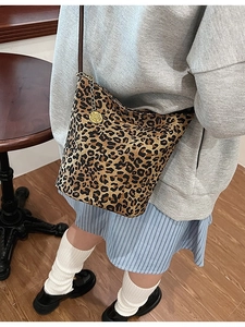 Leopard print bucket bag with brown strap and gold chain detail shown on model