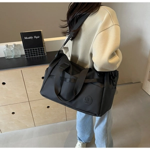 Dettaglio di una borsa da viaggio nera in nylon impermeabile indossata da una modella