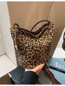 Chic leopard print bucket bag with leather handle and gold chain detail in hand