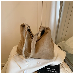 Detail of light brown suede tote bag featuring a decorative knotted shoulder strap design