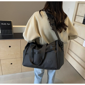 Dettaglio della borsa da viaggio in nylon nero impermeabile con tracolla e logo goffrato