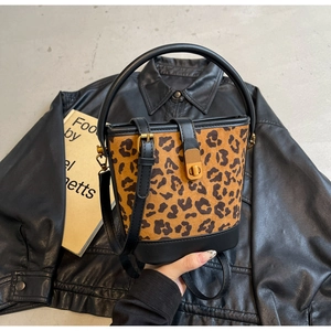 Dettaglio borsa a secchiello leopardata con chiusura a scatto dorata e manico in pelle