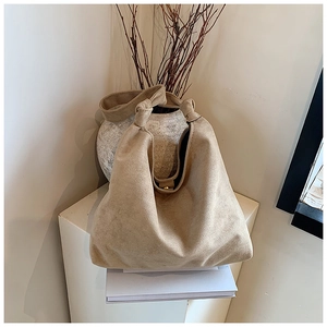 Detail of beige suede hobo bag with unique knotted shoulder strap and gold magnetic bead