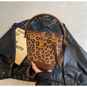 Dettaglio della borsa a secchiello leopardata con finiture in pelle marrone su giacca