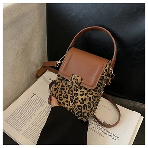 Close-up of leopard print mini crossbody bag with brown leather handles and gold clasp