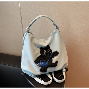 Détail du sac hobo bleu clair avec écusson chat en peluche et tissu synthétique lisse